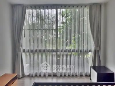 Bright room with large window and sheer curtains overlooking greenery, perfect for a serene living space.