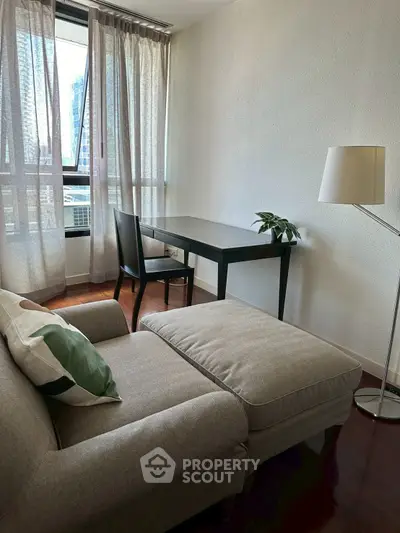 Cozy living room with modern furniture and natural light from large windows.