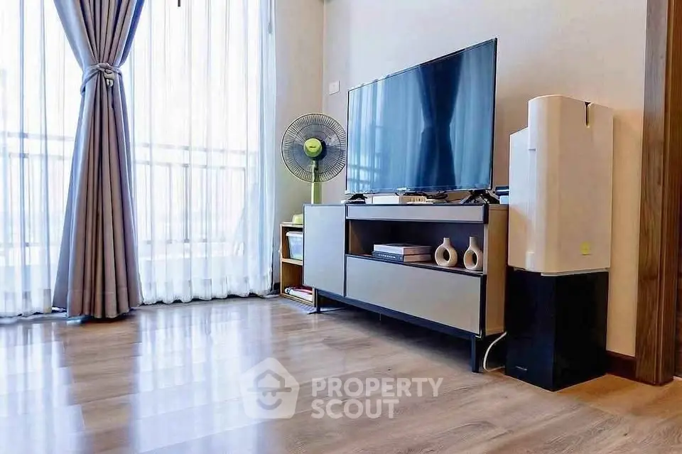 Modern living room with sleek TV stand, large window, and elegant curtains.