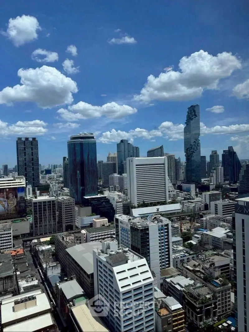 Stunning cityscape view of modern skyscrapers under a vibrant blue sky with fluffy clouds.