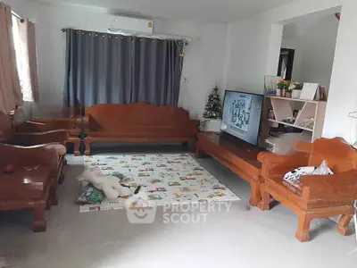 Cozy living room with wooden furniture and TV setup, perfect for family gatherings.