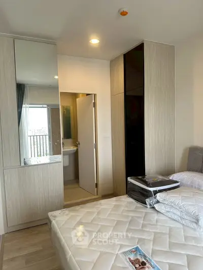 Modern bedroom with stylish wardrobe and glimpse of bathroom, featuring sleek design and ample natural light.