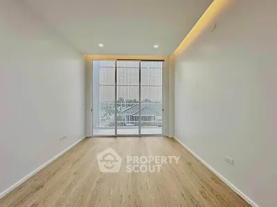 Spacious empty room with large windows and wooden flooring, perfect for customization.