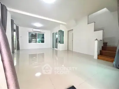 Spacious modern living room with sleek tile flooring and staircase, perfect for family gatherings.
