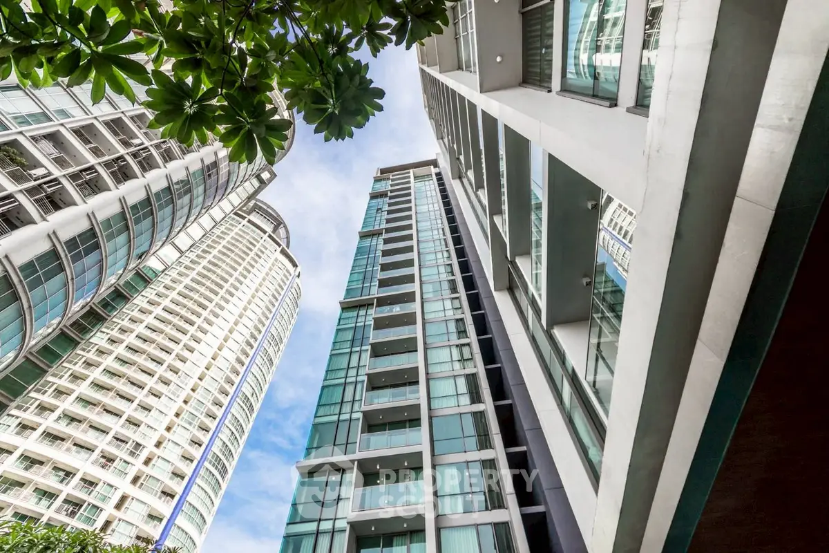Stunning modern high-rise building with glass facade and lush greenery, perfect for urban living.