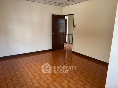 Spacious empty room with wooden flooring and open doorway in a modern home.