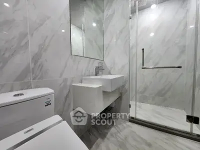 Modern bathroom with marble tiles and glass shower enclosure