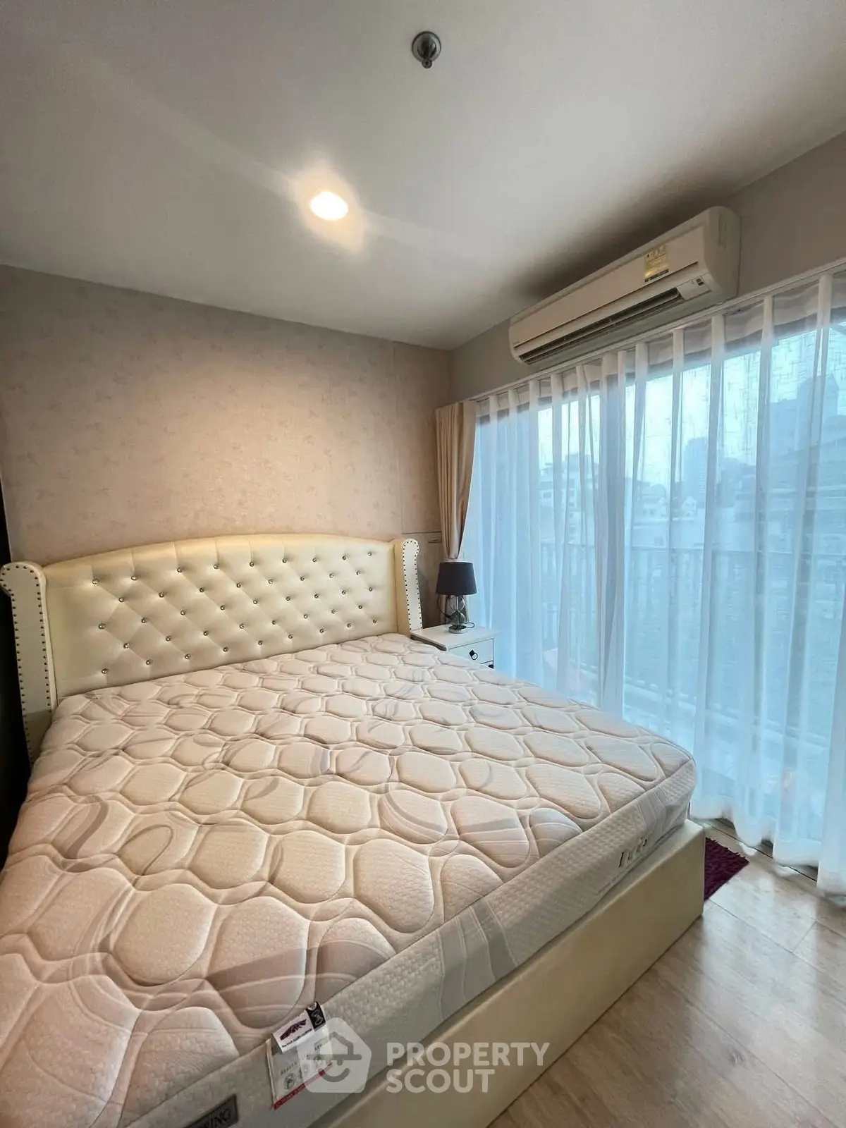 Spacious bedroom with large bed and city view, featuring elegant decor and natural light.