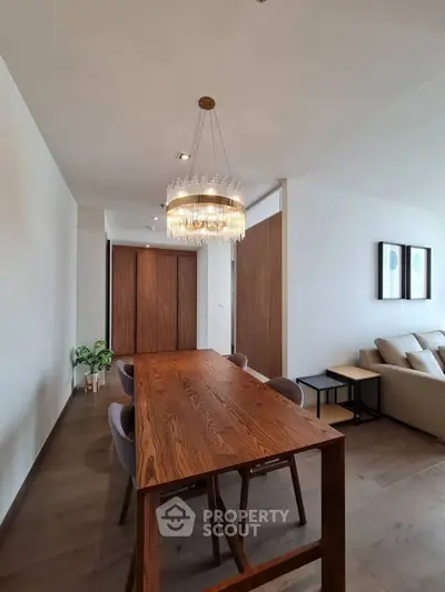 Elegant dining area with modern chandelier and wooden table in a stylish living room.