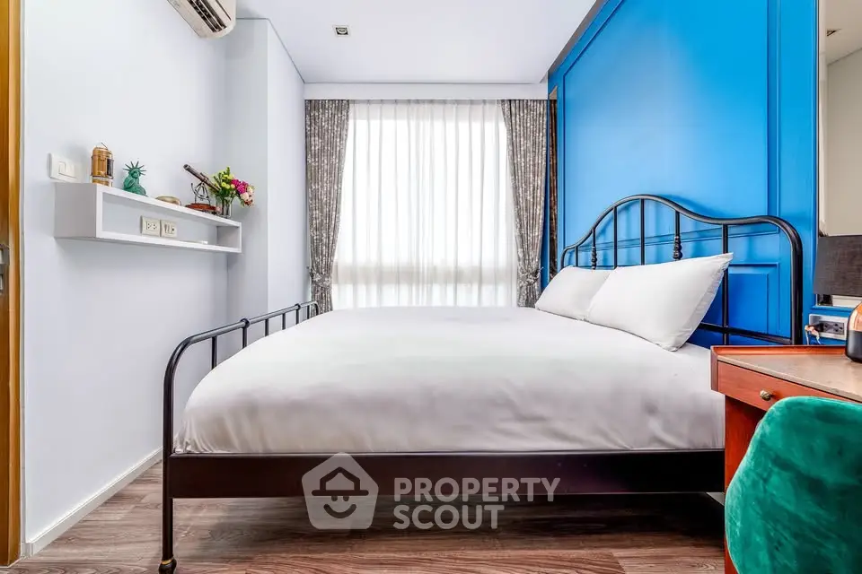 Chic modern bedroom with vibrant blue accent wall and elegant furnishings.