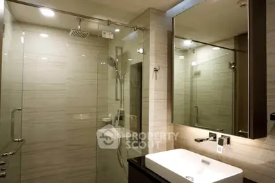 Modern bathroom with glass shower and sleek vanity in luxury apartment.