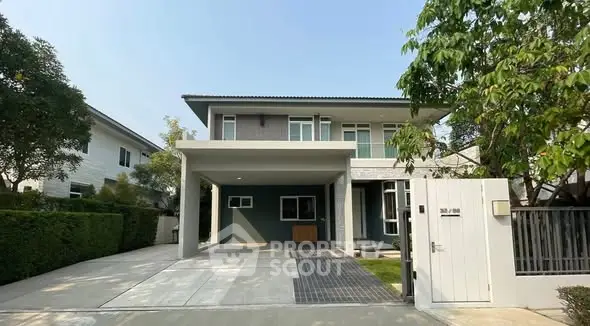 Modern two-story house with spacious driveway and lush greenery