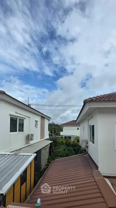 Charming suburban homes with tiled roofs under a bright blue sky.