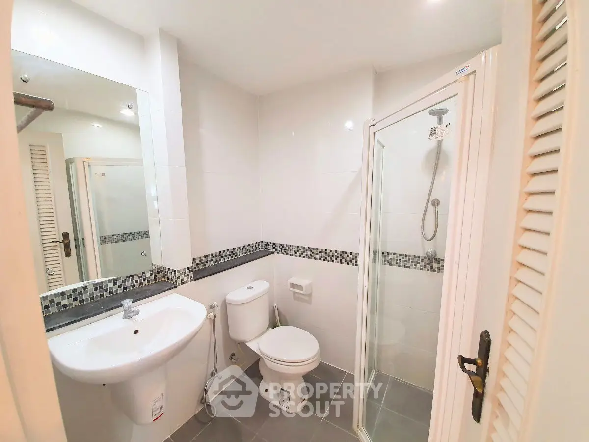 Modern bathroom with shower and sleek fixtures in a bright, tiled space.