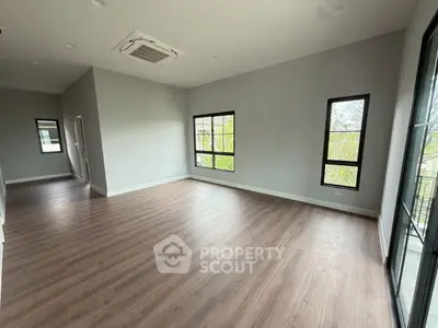 Spacious empty room with large windows and wood flooring, perfect for customization.