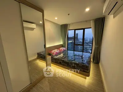Modern bedroom with city view, featuring large window and stylish decor.