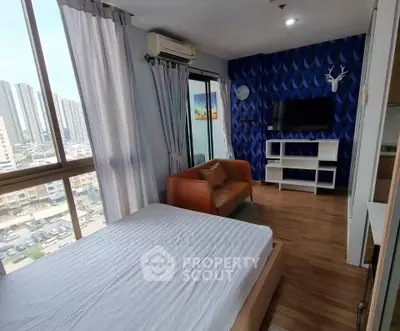 Modern bedroom with city view, stylish blue accent wall, and cozy seating area in a high-rise apartment.