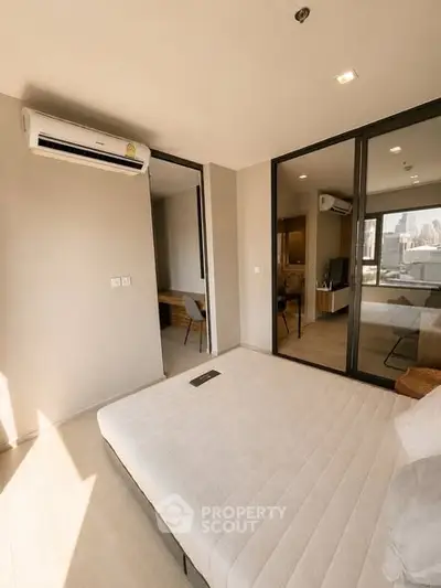 Modern bedroom with large windows and city view, featuring air conditioning and stylish decor.
