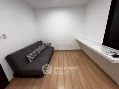 Cozy minimalist living room with sleek wooden flooring and modern gray sofa, perfect for urban living.