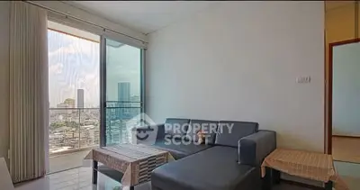 Modern living room with city view and balcony access in high-rise apartment.