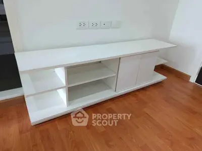 Modern white TV stand with shelves on wooden floor in a stylish living room.