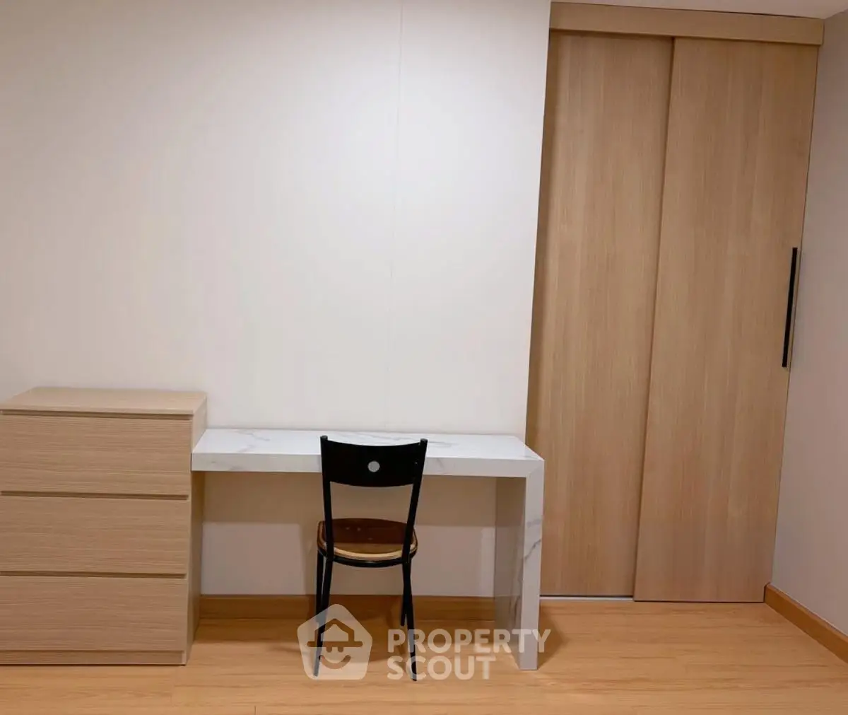 Minimalist study area with desk, chair, and wooden cabinet in modern apartment.