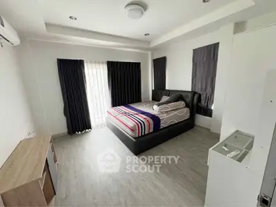 Spacious modern bedroom with stylish decor and ample natural light.