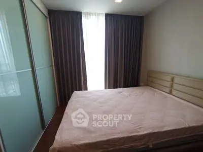 Cozy bedroom with large window and modern sliding wardrobe in a stylish apartment.