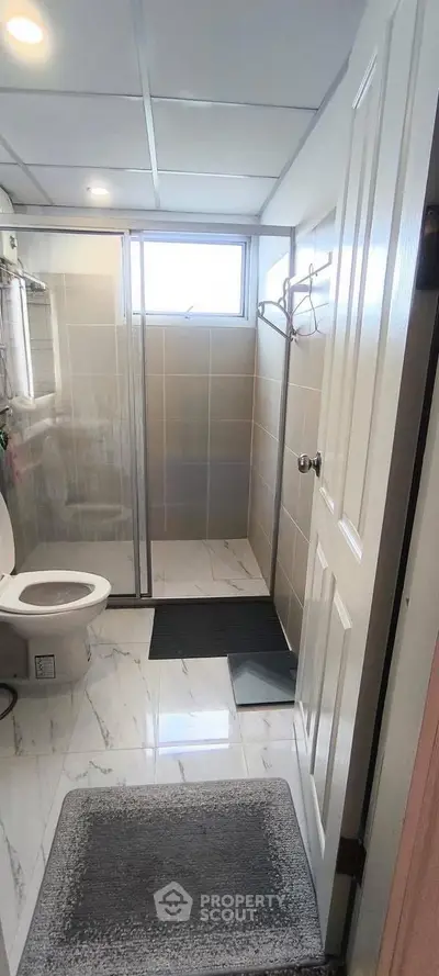 Modern bathroom with glass shower and tiled flooring in a stylish home.