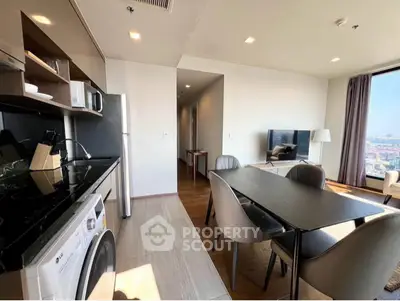 Modern open-layout kitchen and living room with city view, featuring sleek appliances and stylish furniture.
