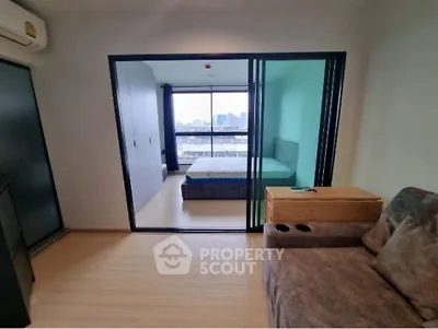 Modern apartment with sliding glass doors and city view, featuring cozy living area and bedroom.