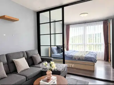 Modern living room with sliding glass doors leading to a cozy bedroom, featuring stylish decor and natural light.
