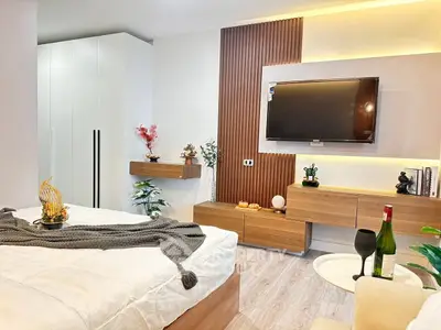 Modern bedroom with stylish decor and wall-mounted TV, featuring cozy ambiance and elegant furnishings.