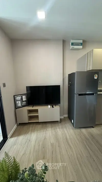 Modern living room with sleek TV setup and stainless steel fridge, perfect for contemporary urban living.