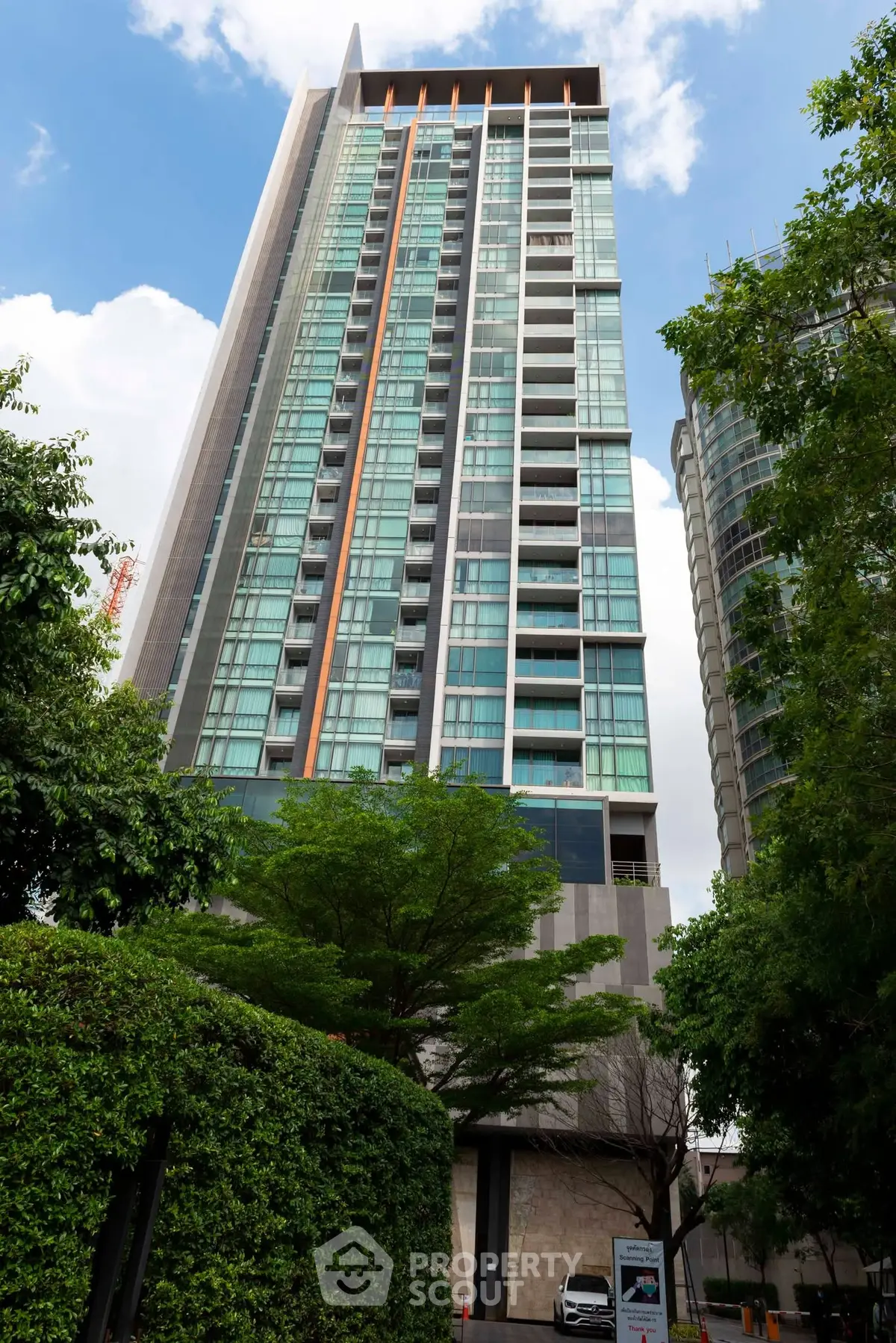 Stunning high-rise building with modern glass facade and lush greenery, perfect for urban living.
