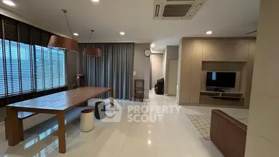 Spacious modern living room with stylish wooden dining table and sleek entertainment center.