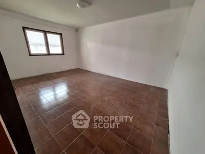 Spacious empty room with tiled floor and large window, perfect for customization.