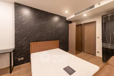 Modern bedroom with stylish black marble accent wall and wooden flooring, featuring a comfortable bed and sleek wardrobe.