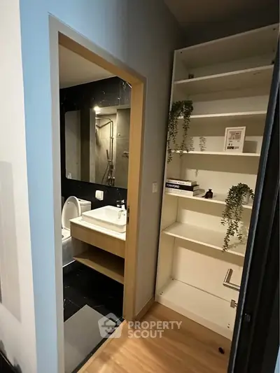 Modern bathroom with sleek design and adjacent storage shelves, perfect for urban living.