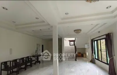 Spacious living room with elegant staircase and large windows, perfect for natural light and modern living.