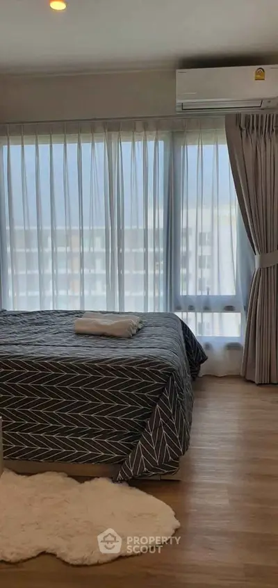 Modern bedroom with large windows and stylish decor in a high-rise apartment.