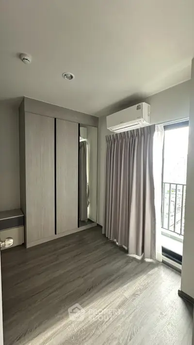 Spacious bedroom with large window and modern wardrobe in a bright apartment.
