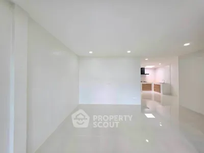 Spacious open-plan living area with modern kitchen in a bright, minimalist apartment.