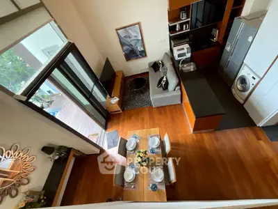 Modern open-plan living room with kitchen and balcony, featuring wooden flooring and stylish decor.