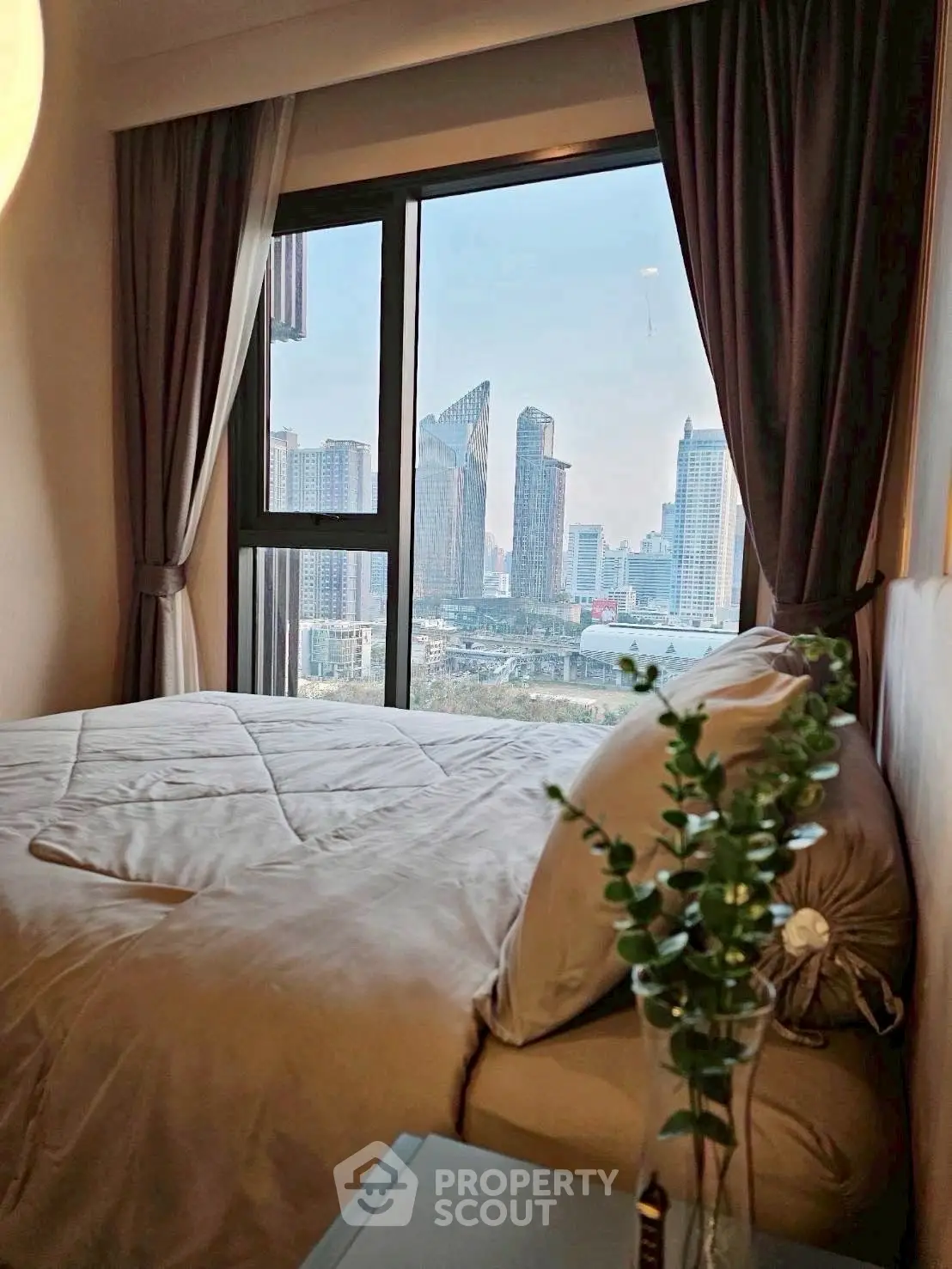 Cozy bedroom with city view, modern decor and large window, perfect urban retreat.