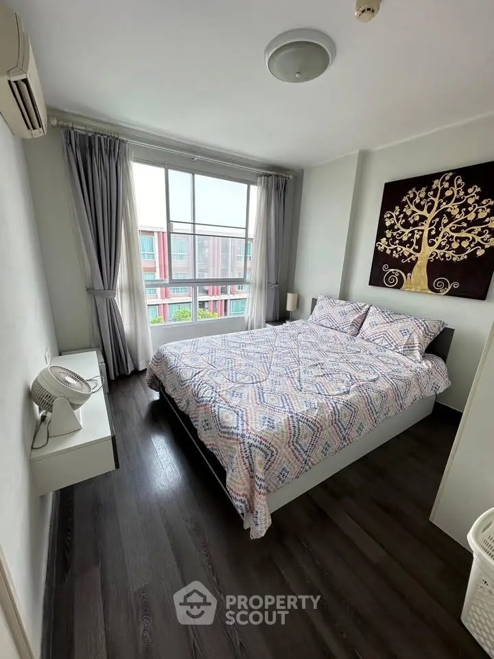 Cozy bedroom with modern decor and large window offering natural light and city view.