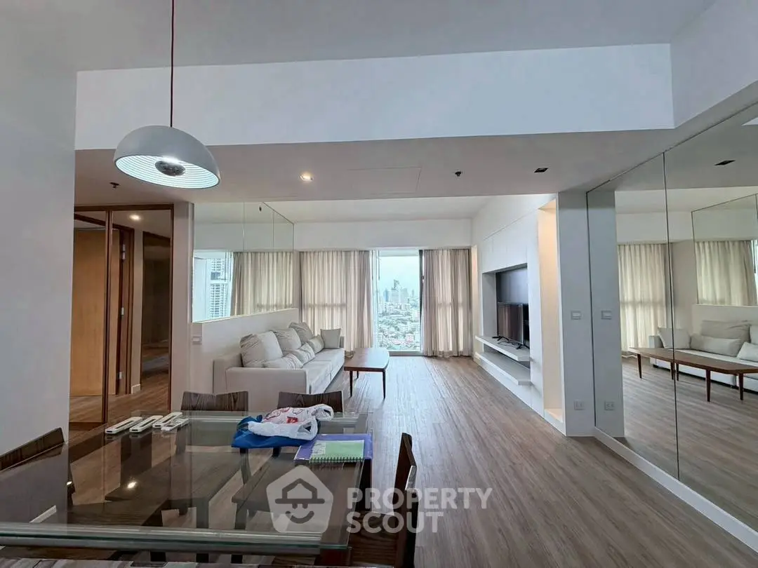 Spacious modern living room with city view, elegant dining area, and stylish decor in high-rise apartment.