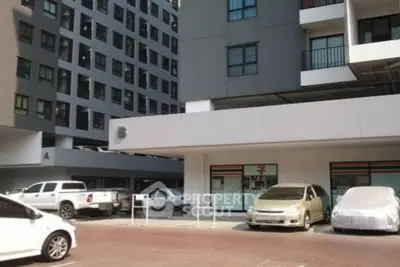 Modern apartment building with parking area and multiple vehicles in front.