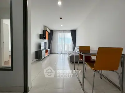 Modern living room with sleek furniture and natural light from large window.