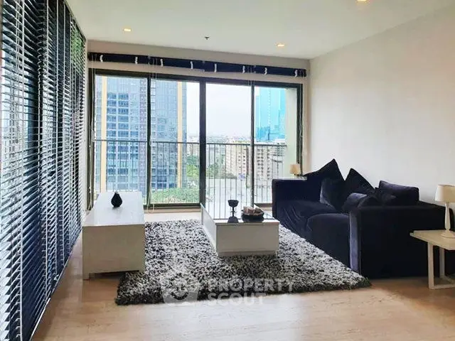 Modern living room with large windows and city view, featuring stylish furniture and cozy decor.